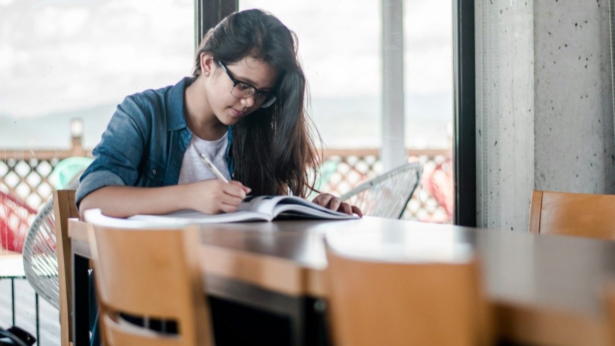 Student working through a textbook at a table