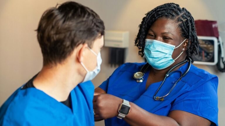 Two nurses in blue scrubs in a clinical setting